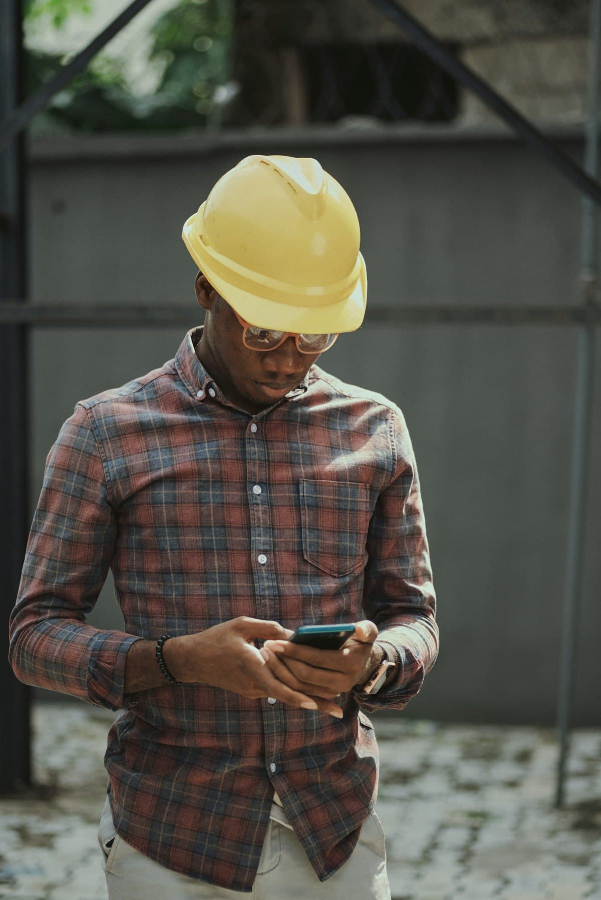A contractor in a hard hat looking at his phone