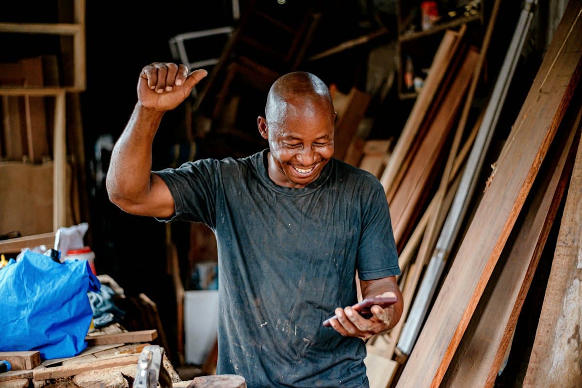 A business owner smiling at his phone in his workshop